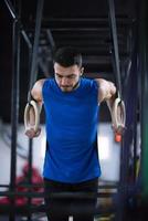 hombre haciendo pull ups con anillos de gimnasia foto