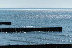 Breakwater on beach. Wooden sea separator. Beautiful seascape. Protection holidaymakers from effects of both weather and longshore drift. photo