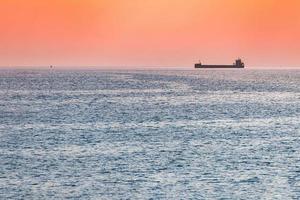 Little tugboat and big cargo ship. Beautiful sunset over sea. Breathtaking travel view, copy space. photo