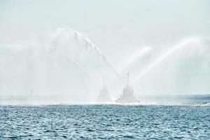 remolcadores rociando chorros de agua, demostrando cañones de agua contra incendios, botes de bomberos rociando espuma foto