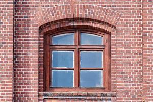 una ventana de cristal arqueada en la pared de ladrillo roja vieja foto