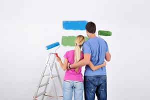 pareja feliz pintando una pared en su nuevo hogar foto