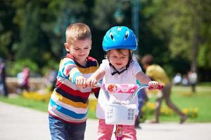 niño y niña en el parque aprendiendo a andar en bicicleta foto