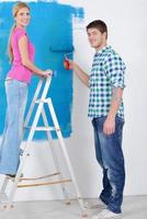 pareja feliz pintando una pared en su nuevo hogar foto