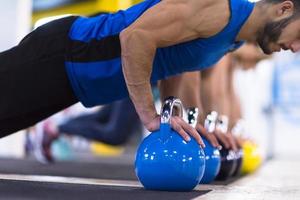 young athletes doing pushups with kettlebells photo