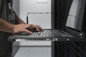 Close up on Data Center Engineer hands Using keyboard on a supercomputer Server Room Specialist Facility with Male System Administrator Working with Data Protection Network for Cyber Security. photo