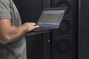 Data Center Engineer Using Laptop Computer. Server Room Specialist Facility with Korean Male System Administrator Working with Data Protection Network for Cyber Security. photo