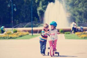 Boy and girl in park learning to ride a bike photo