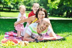 Feliz pareja joven con sus hijos divertirse en el parque foto