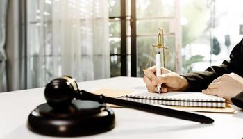 Business and lawyers discussing contract papers with brass scale on desk in office. Law, legal services, advice, justice and law concept picture with film grain effect photo