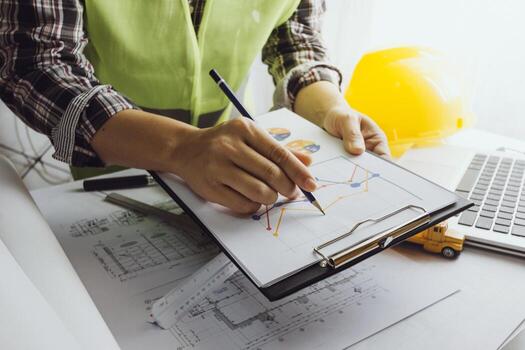 Two colleagues discussing data working and tablet, laptop with on on architectural project at construction site at desk in office photo