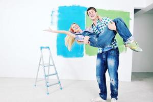 pareja feliz pintando una pared en su nuevo hogar foto