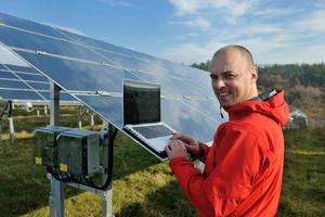 engineer using laptop at solar panels plant field photo