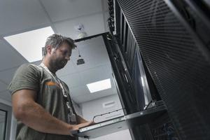 Close up on Data Center Engineer hands Using keyboard on a supercomputer Server Room Specialist Facility with Male System Administrator Working with Data Protection Network for Cyber Security. photo