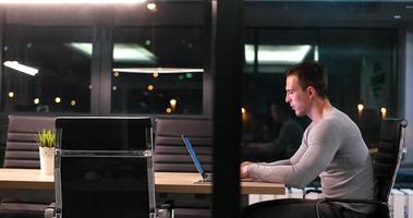 hombre trabajando en una laptop en una oficina oscura foto