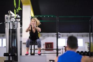 woman working out with personal trainer jumping on fit box photo