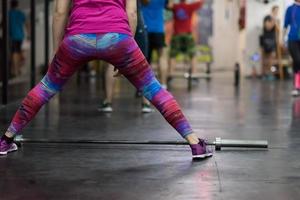 a group of people exercise with an empty bar photo