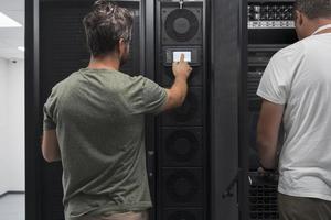 Data Center Engineer Using Laptop Computer. Server Room Specialist Facility with Korean Male System Administrator Working with Data Protection Network for Cyber Security. photo