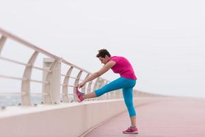 mujer estirándose y calentándose en el paseo marítimo foto