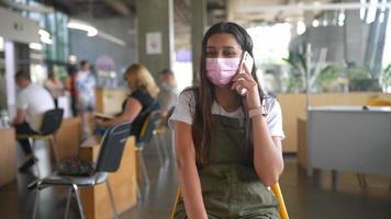 mujer con máscara en el restaurante, habla por teléfono video