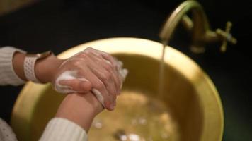 Woman wash hands in golden sink and faucet video