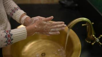 Frau wäscht sich die Hände in goldenem Waschbecken und Wasserhahn video