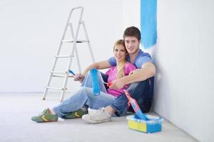 pareja joven feliz relajándose después de pintar en un nuevo hogar foto