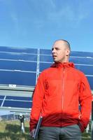 engineer using laptop at solar panels plant field photo