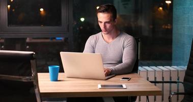 man working on laptop in dark office photo