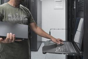 Close up on Data Center Engineer hands Using keyboard on a supercomputer Server Room Specialist Facility with Male System Administrator Working with Data Protection Network for Cyber Security. photo