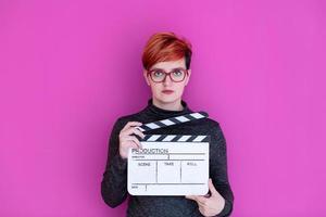 Mujer que sostiene la badajo de la película aislado sobre fondo de color rosa foto