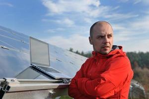 ingeniero que usa una computadora portátil en el campo de la planta de paneles solares foto