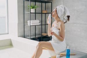 Girl enjoys smell of body lotion perfume and has rest in bathroom. Tranquility and relaxation. photo