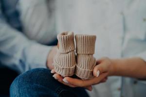 la mujer y el hombre irreconocibles esperan que el bebé tenga pequeños botines. concepto de paternidad de maternidad familiar. futuros padres. nacimiento foto