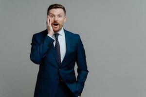 Surprised businessman in suit looking at camera with shocked face expression photo