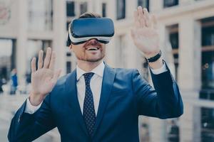 Office worker in formal suit exploring virtual world with VR glasses while relaxing outdoors photo