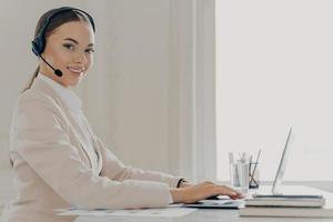 Smiling call center agent in headset consulting client photo