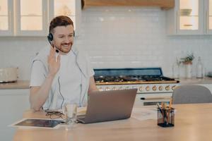 Happy young man having lesson during elearning on laptop at home photo