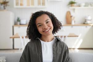 retrato de niña afro feliz en casa. peinado rizado, sonrisa optimista y emociones positivas. foto