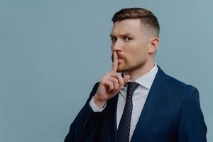 Businessman looking at camera and showing shh sign photo