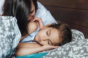 mujer con niña dormida en la cama foto