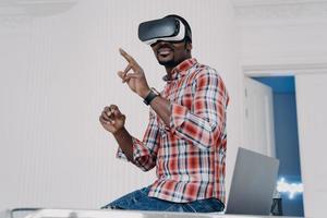 Interactive virtual reality goggles. African student in vr glasses at home office. photo