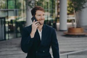 Confident man entrepreneur dressed in formal clothes makes phone call in roaming photo