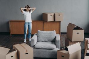 European woman has headache from moving alone. Young lady is exhausted with boxes unloading. photo