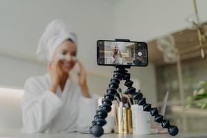 Smartphone screen with female beauty blogger in bathrobe recording video about skin care for her vlog photo