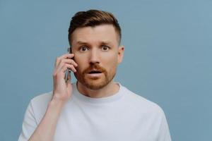 hombre sorprendido recibiendo noticias conmocionadas mientras habla con alguien por teléfono móvil foto