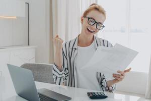 Overjoyed redhead woman exclaiming yes, celebrating money refund or last last mortgage payment photo