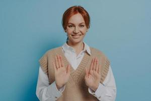 Positive young 30s red haired woman saying no while standing isolated on blue wall background photo
