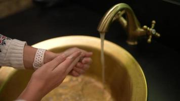 Woman wash hands in golden sink and faucet video