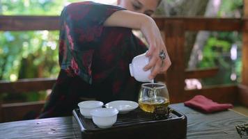 Tea ceremony performed by a young brunette woman on outdoor terrace video